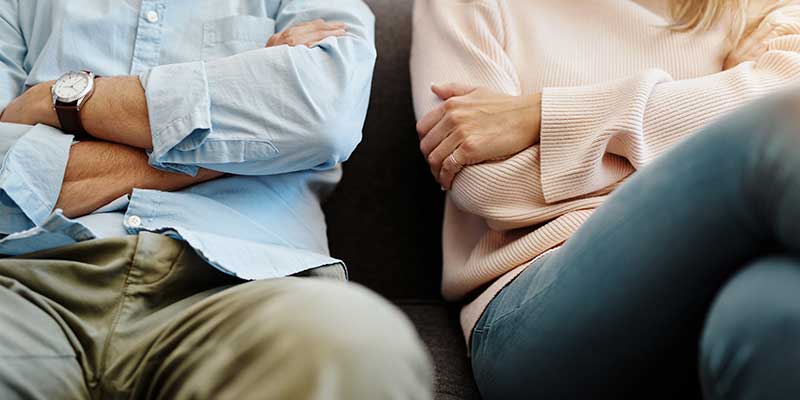 Couple sitting next to each other with arms crossed