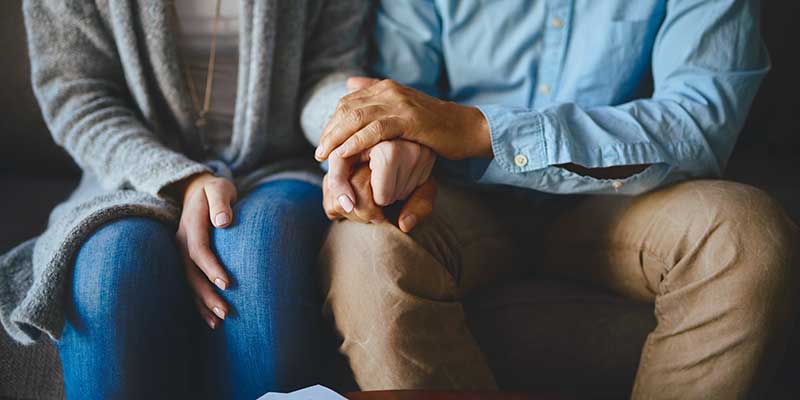Couple holding hands sitting on couch